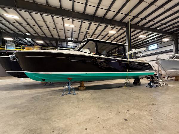 MJM 3 2022 MJM 3 boat in a warehouse, black hull with turquoise bottom, on stands.