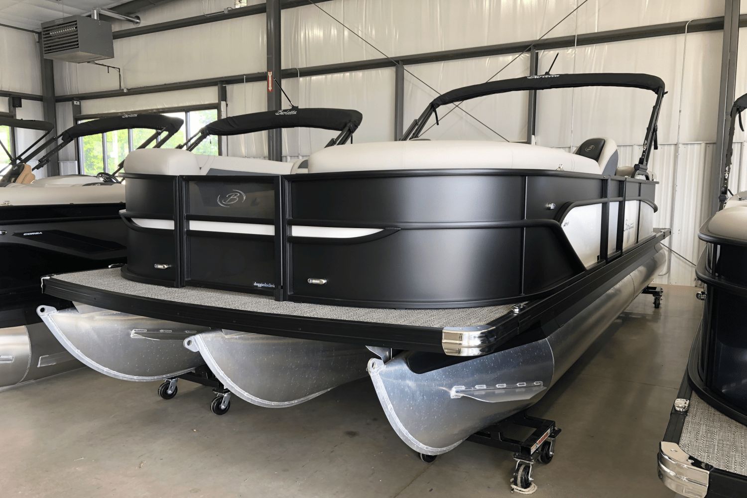 Barletta Cabrio 2025 Barletta Cabrio pontoon boat in showroom, featuring sleek black design and modern amenities.