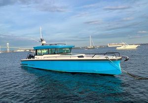 Axopar 37 XC 2020 Axopar 37 XC boat in blue, anchored on calm water with a bridge in the background.