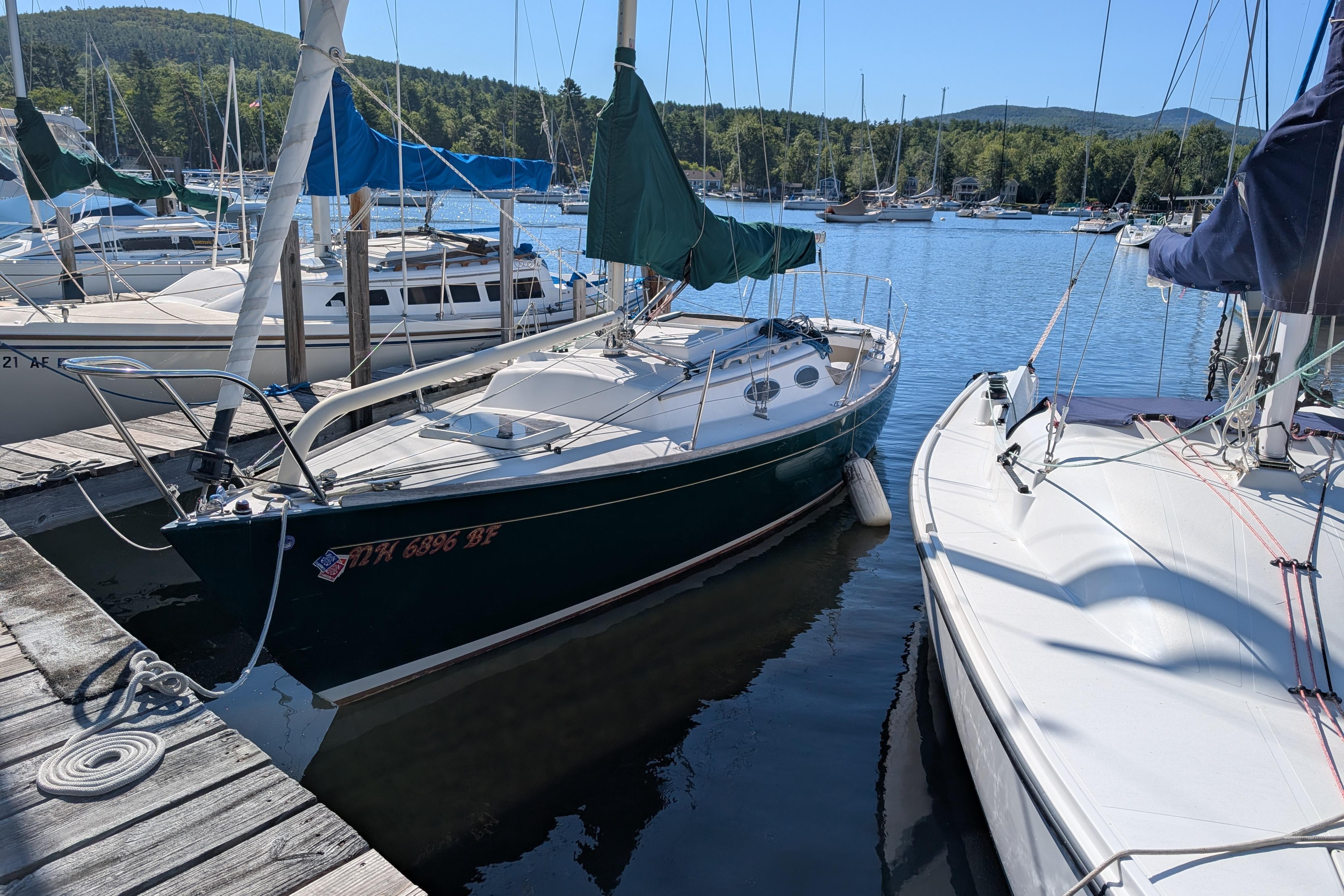 Alerion 28 Sailboat Alerion 28 (2001) docked at a scenic marina with forested hills.