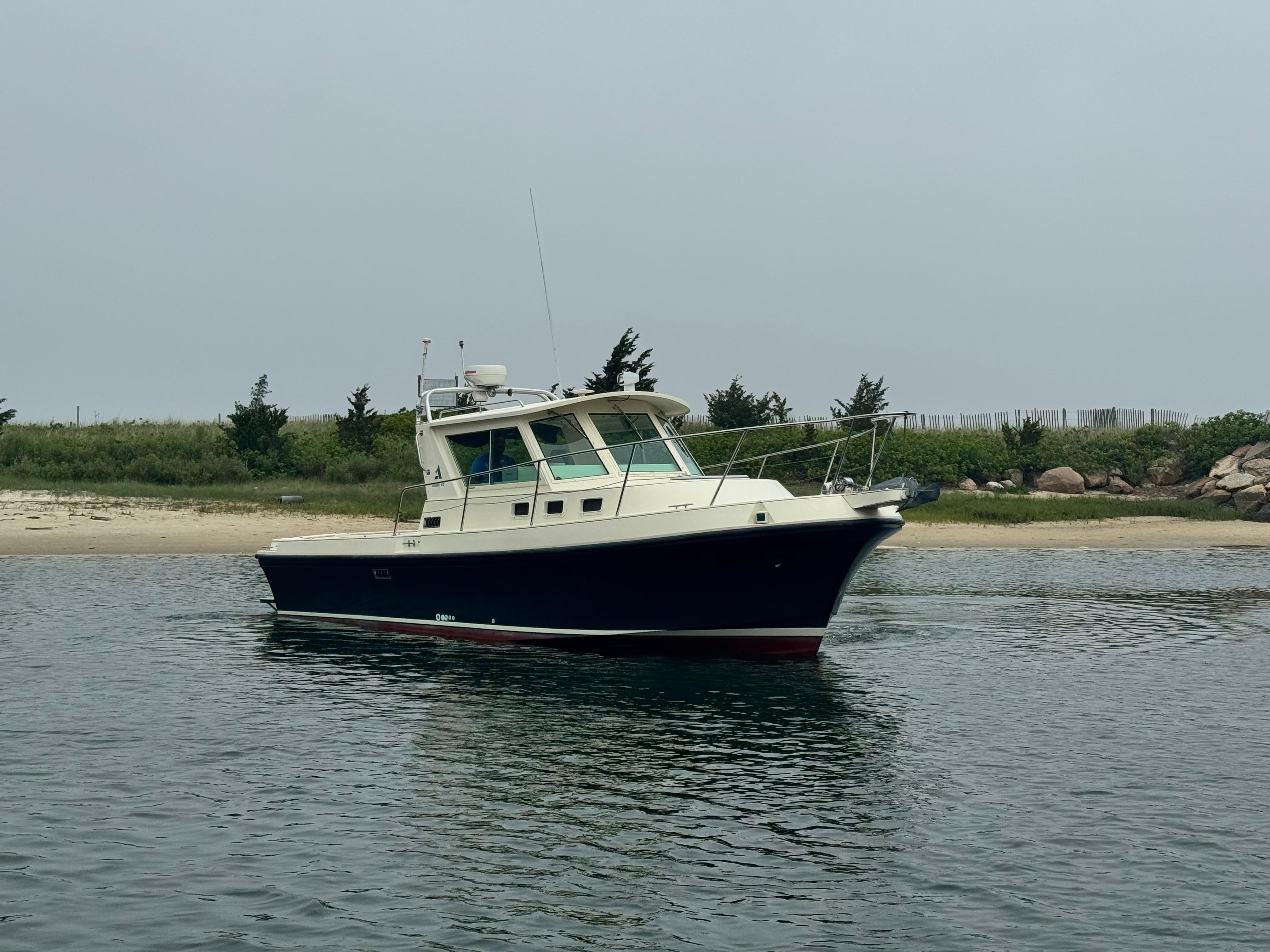 Albin 28 2001 Albin 28 boat anchored near a sandy shore with greenery in the background.