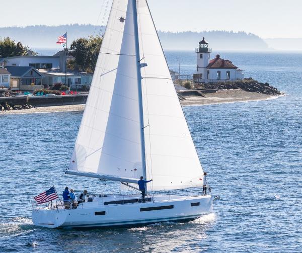 Jeanneau Sun Odyssey 490 2024 Jeanneau Sun Odyssey 490 sailing near a coastal lighthouse.