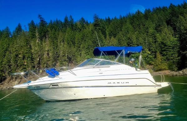 Maxum 2400 SCR 2000 Maxum 2400 SCR boat on calm water, surrounded by lush green forest.