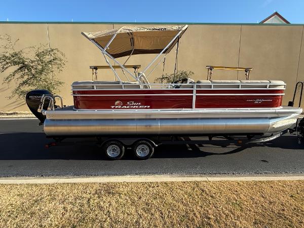 Sun Tracker Party Barge 24 DLX 2024 Sun Tracker Party Barge 24 DLX pontoon boat on trailer, side view.