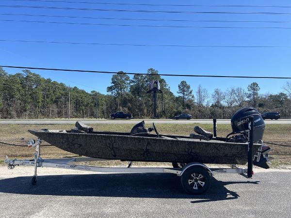 Xpress XP180 2025 Xpress XP180 boat on trailer, parked roadside with trees and cars in background.