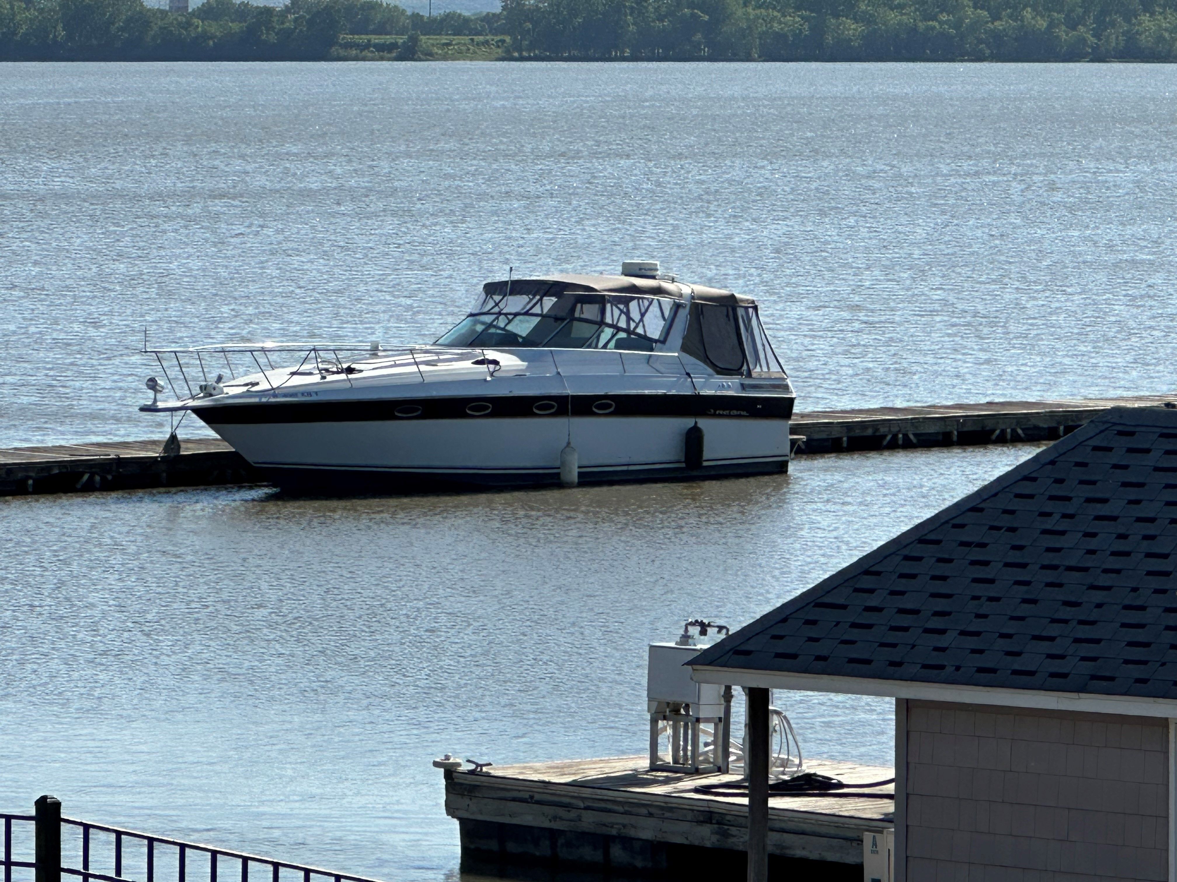 Regal Commodore A 1989 Regal Commodore boat docked on a calm lake near a wooden pier.