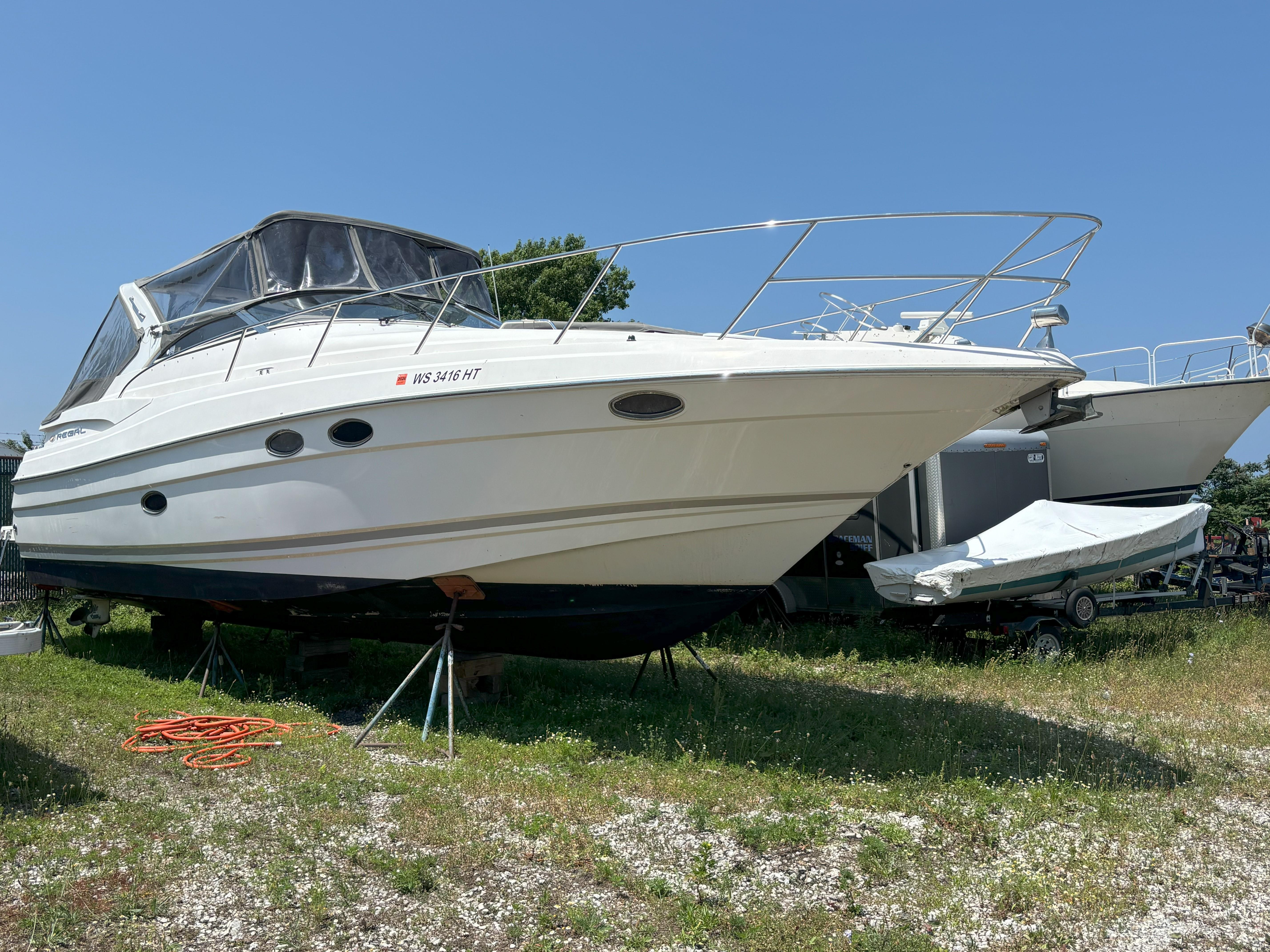 Regal Commodore 3560 IO 2006 Regal Commodore 3560 IO boat on stands, outdoors, under clear blue sky.