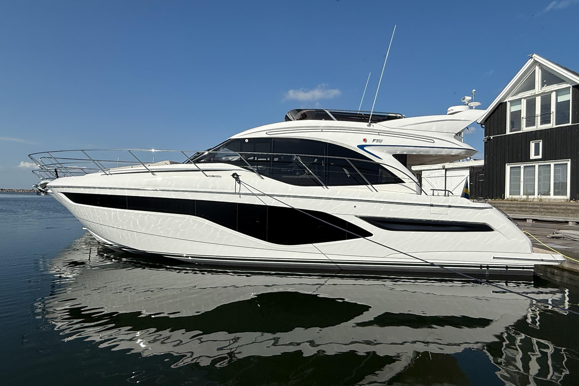 Princess F50 2024 Princess F50 yacht docked by a modern waterfront house.