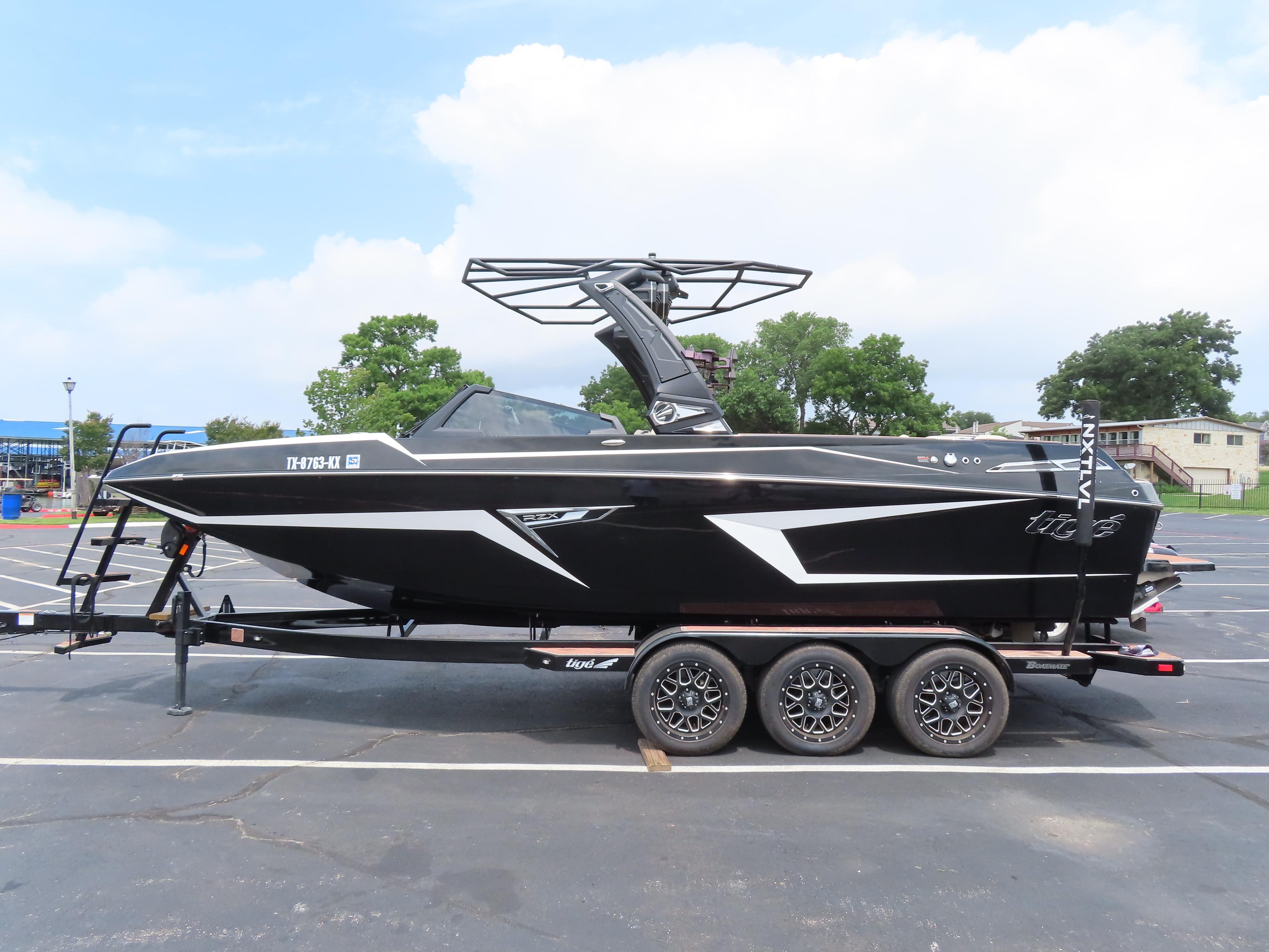Tigé 24RZX 2023 Tigé 24RZX boat on trailer in parking lot, side view.