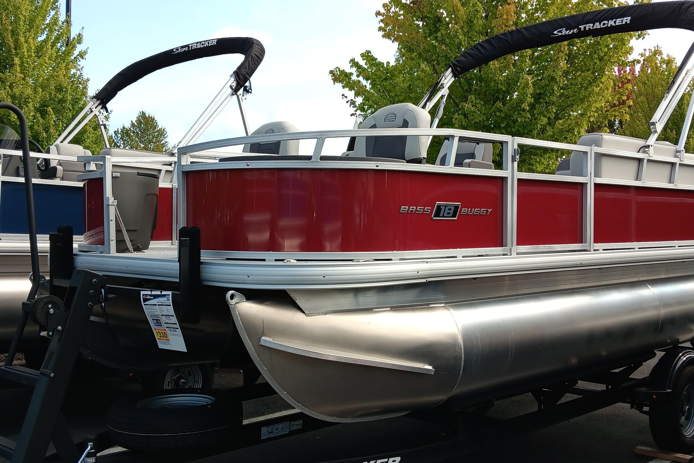 Sun Tracker Bass Buggy 18 DLX 2026 Sun Tracker Bass Buggy 18 DLX pontoon boat, red exterior, on trailer, outdoor display.