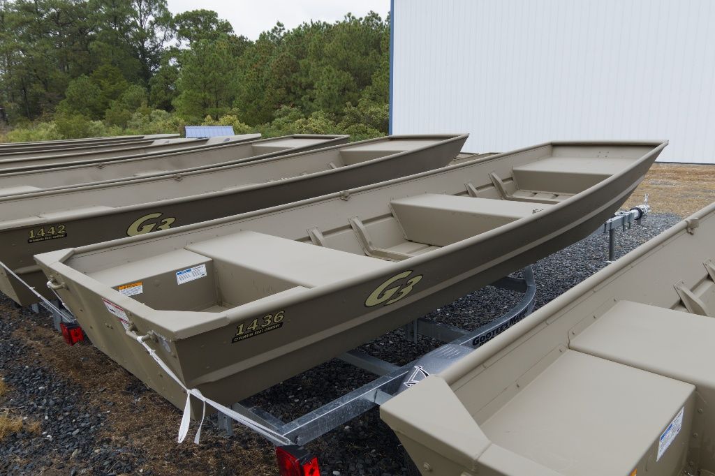 G3 1436 Row of 2026 G3 1436 boats on trailers, outdoors near trees.