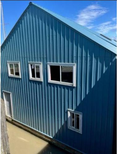Custom Boathouse Blue custom boathouse with windows, built in 2012, under a clear sky.
