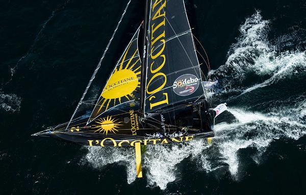 Black Pepper Imoca Sailing yacht "Black Pepper Imoca 2025" navigating through ocean waves, featuring L'Occitane branding.