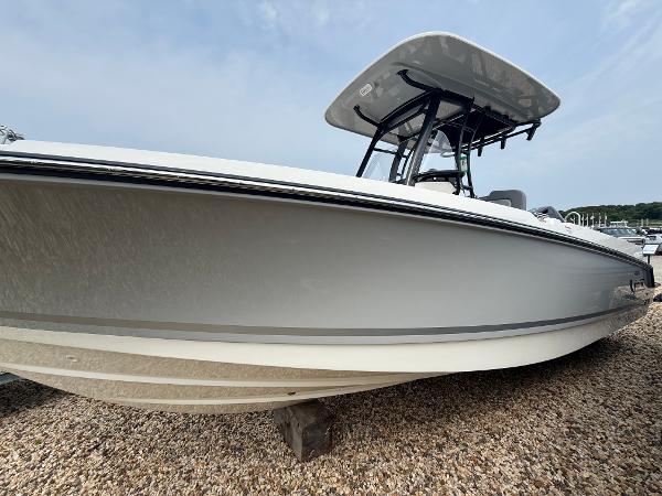 Boston Whaler 230 Outrage 2025 Boston Whaler 230 Outrage boat on gravel, side view with T-top canopy.