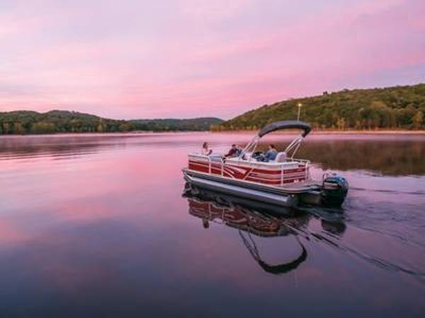 Ranger 223C 2023 Ranger 223C pontoon boat cruising on a serene lake at sunset.