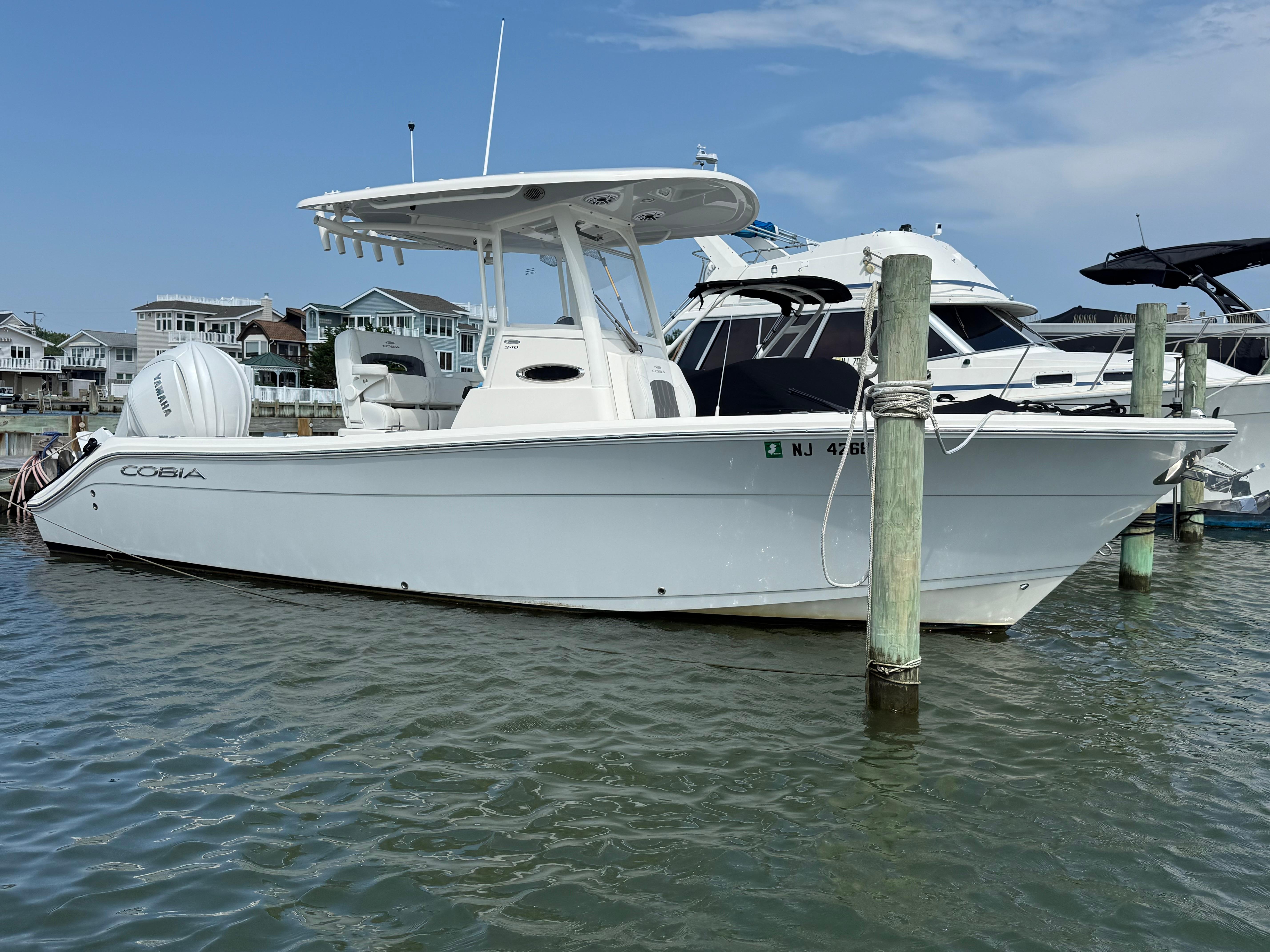 Cobia 240 Center Console 2023 Cobia 240 Center Console boat docked in marina, clear sky background.