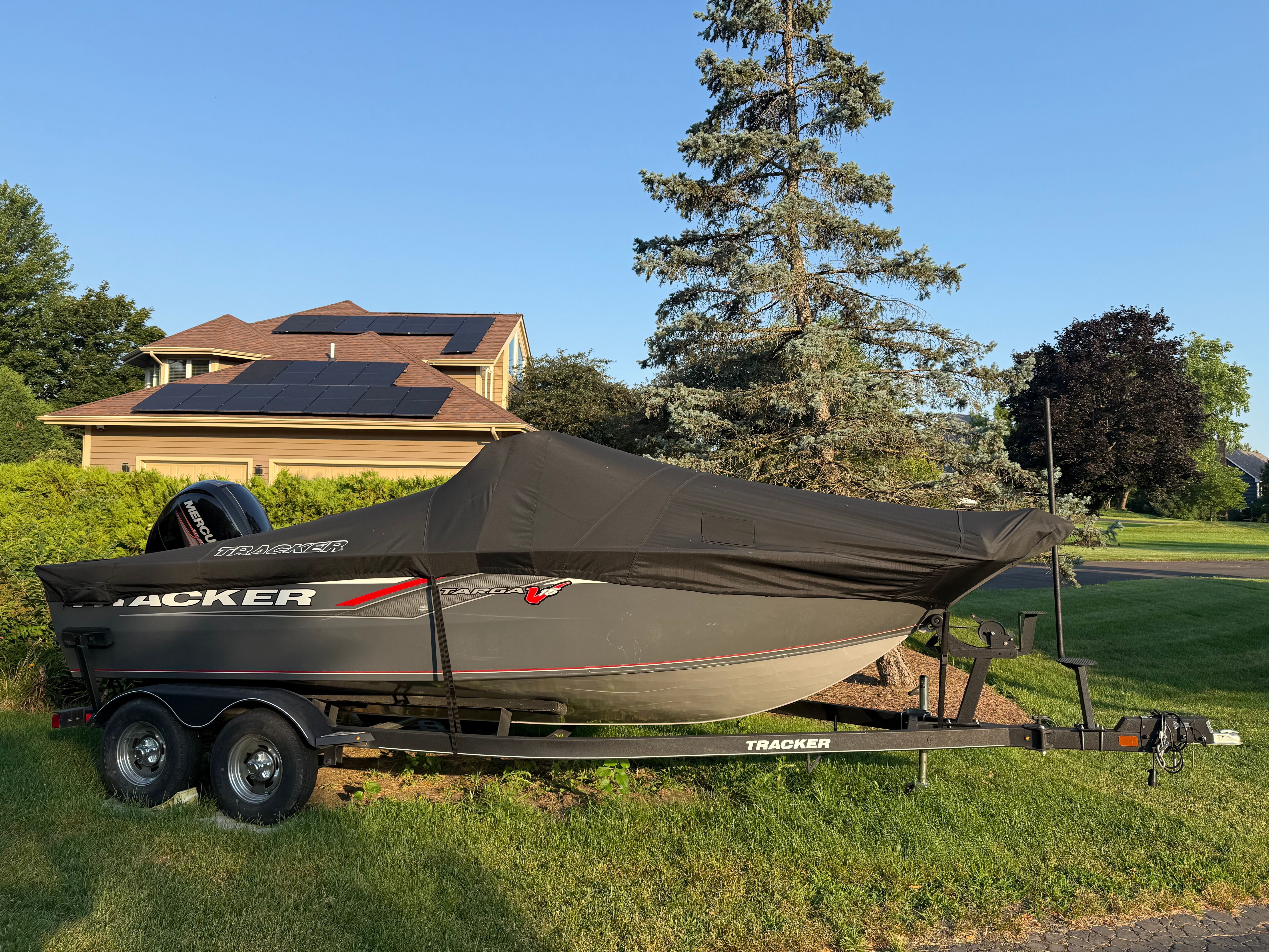 Tracker Targa V-18 WT 2018 Tracker Targa V-18 WT boat on trailer, covered, near house with solar panels.