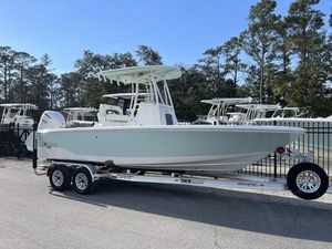 Pathfinder 2400 Open 2025 Pathfinder 2400 Open boat on trailer, parked outdoors, surrounded by trees and other boats.