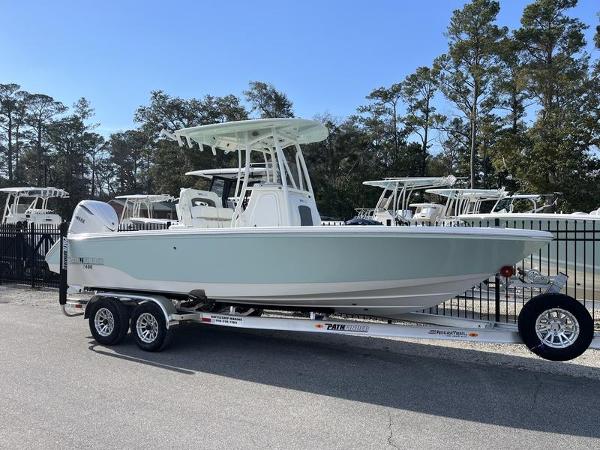 Pathfinder 2400 Open 2025 Pathfinder 2400 Open boat on trailer, parked outdoors, surrounded by trees and other boats.