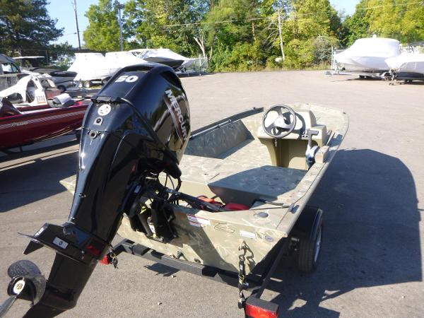 Tracker Grizzly 1648 SC 2024 Tracker Grizzly 1648 SC boat with Mercury outboard motor in a parking lot.