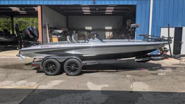 Triton 21XP Patriot 2025 Triton 21XP Patriot boat on trailer, parked outside a blue garage.