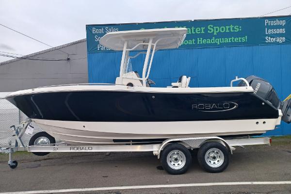 Robalo R230 Center Console 2025 Robalo R230 Center Console boat on trailer, parked outside a marine store.