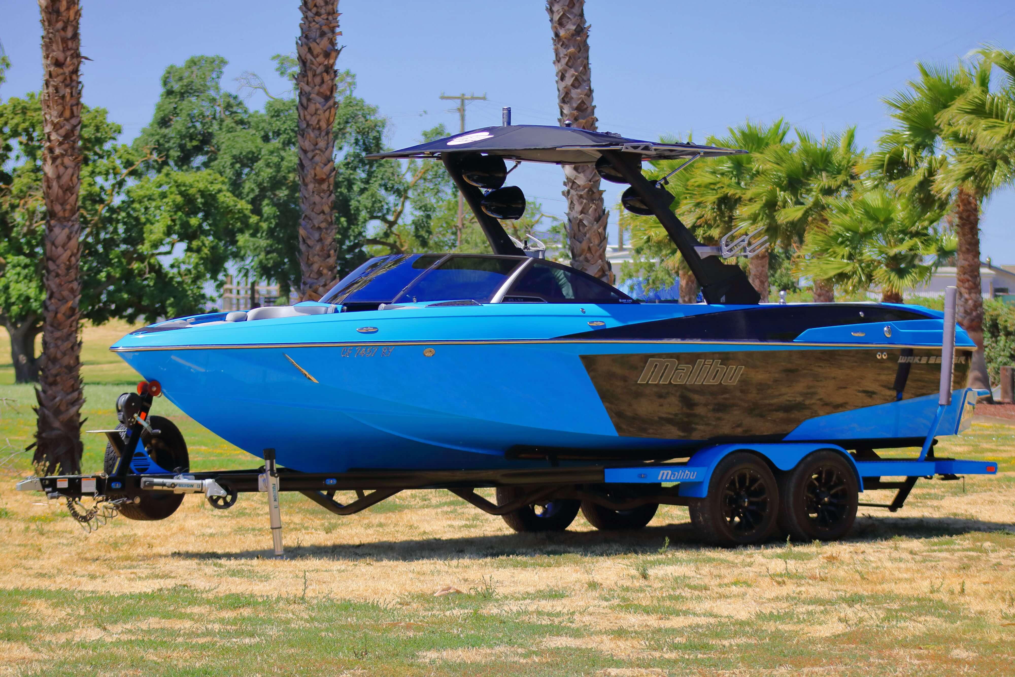 Malibu Wakesetter 25 LSV 2017 Malibu Wakesetter 25 LSV boat on trailer, parked near palm trees.