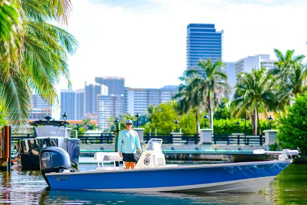 Hewes Redfisher 21 2022 Hewes Redfisher 21 boat on water, city skyline and palm trees in background.