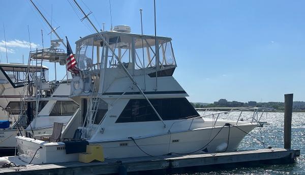 Viking Convertible 1990 Viking Convertible yacht docked at marina with American flag.