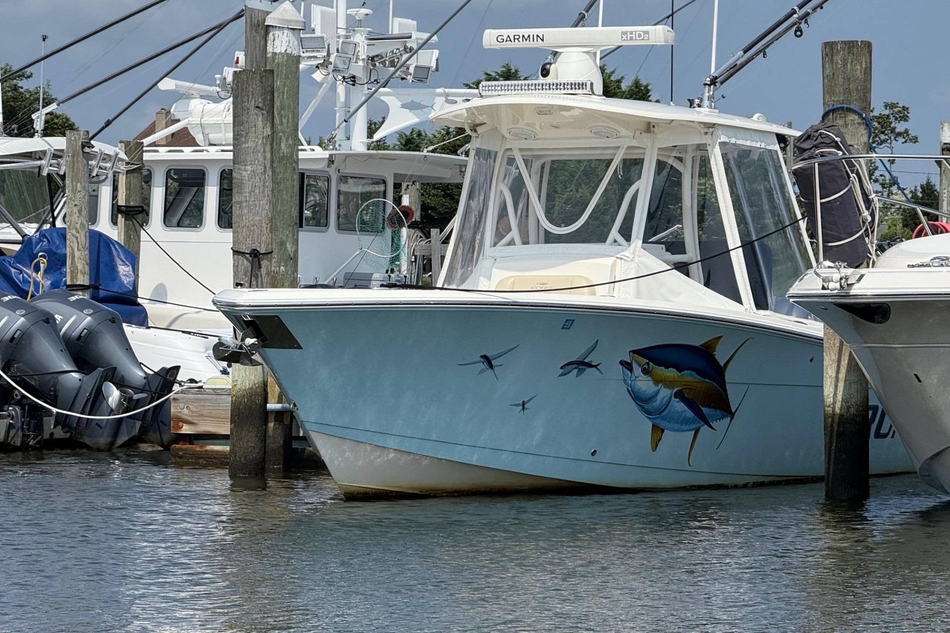 Cobia 277 Center Console 2019 Cobia 277 Center Console boat docked, featuring a vibrant fish mural.