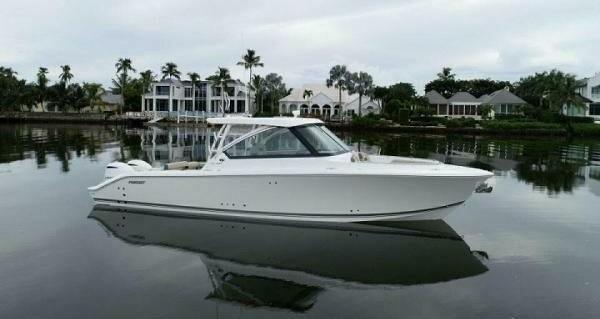 Pursuit DC 325 Dual Console 2019 Pursuit DC 325 Dual Console boat on calm water, with waterfront homes in the background.