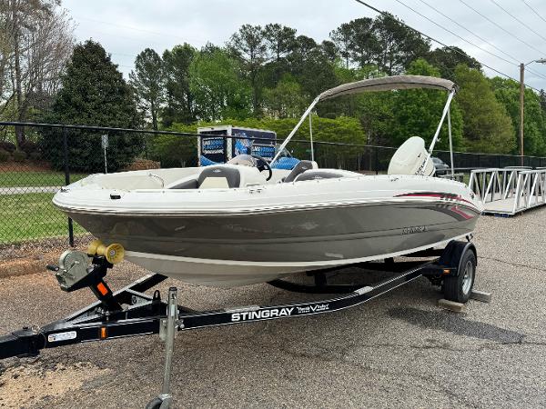 Stingray 182 SC 2019 Stingray 182 SC boat on trailer, parked outdoors with trees in background.