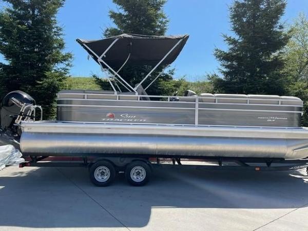 Sun Tracker Party Barge 24 DLX 2024 Sun Tracker Party Barge 24 DLX pontoon boat on trailer, parked outdoors.