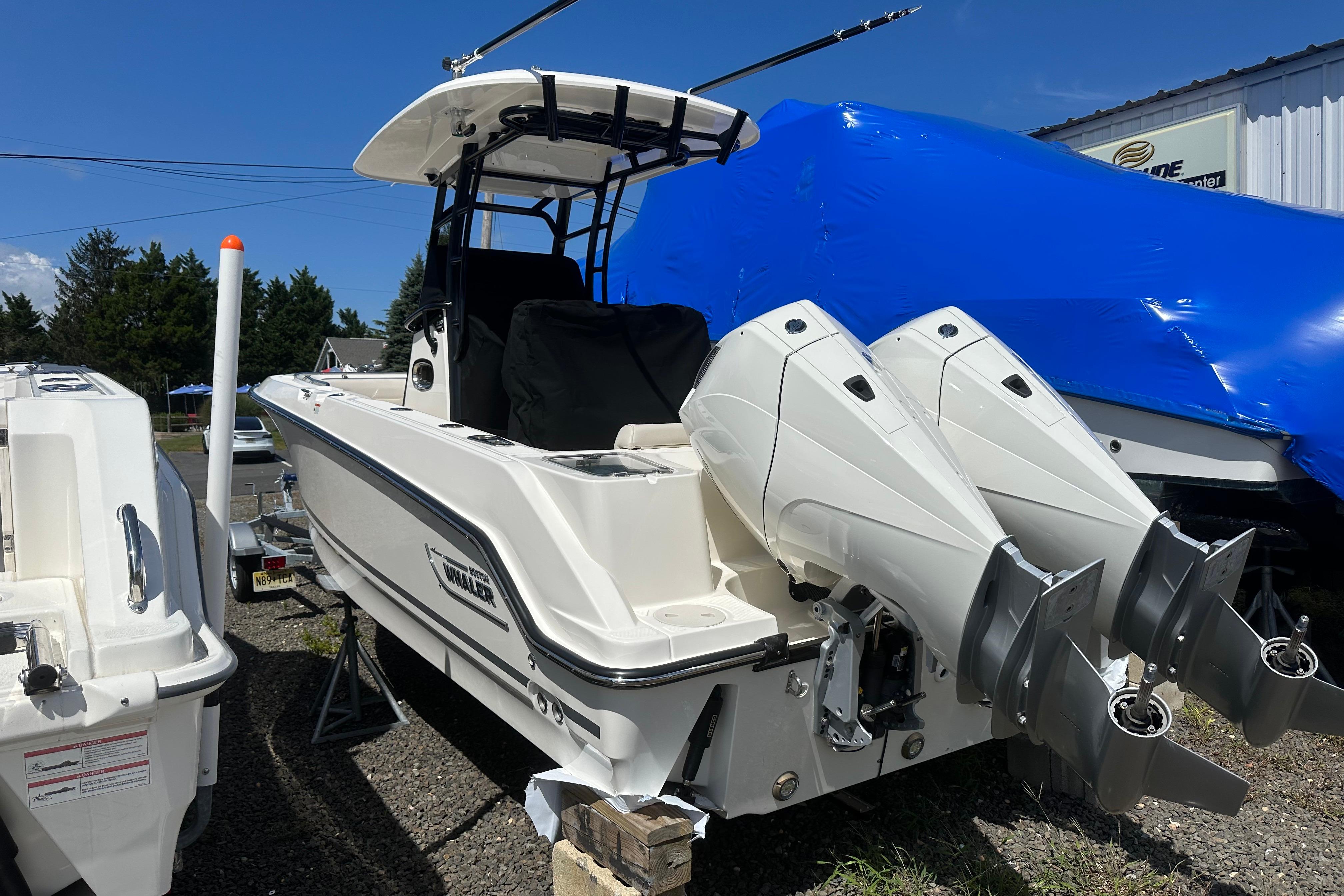 Boston Whaler 230 Outrage 2026 Boston Whaler 230 Outrage boat with dual engines, parked outdoors.