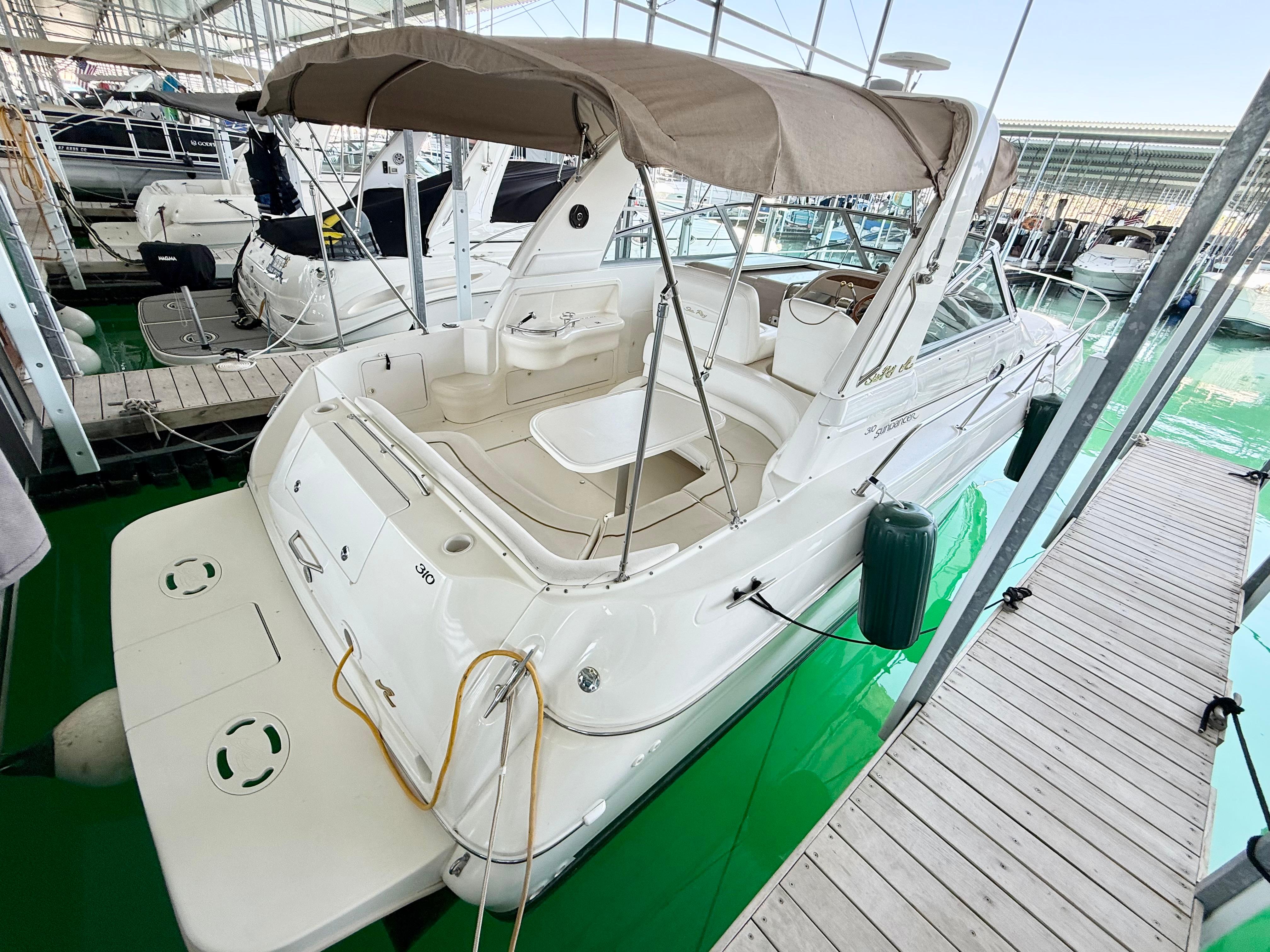 Sea Ray 310 Sundancer 1999 Sea Ray 310 Sundancer docked in a marina, featuring a beige canopy.
