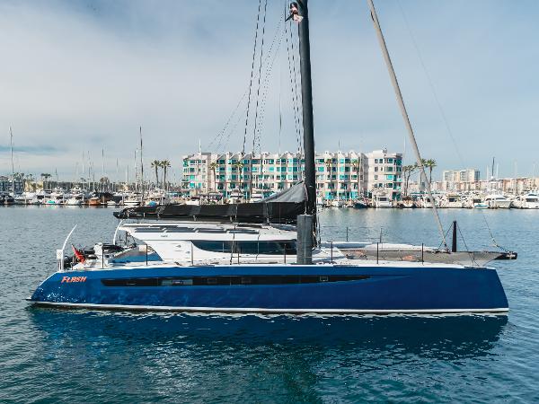 HH Catamarans HH66 2017 HH Catamarans HH66 sailing in marina, sleek design, blue hull, modern waterfront buildings.