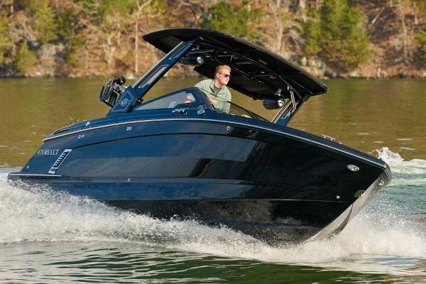 Cobalt R8 Surf 2026 Cobalt R8 Surf boat cruising on a lake with a driver.