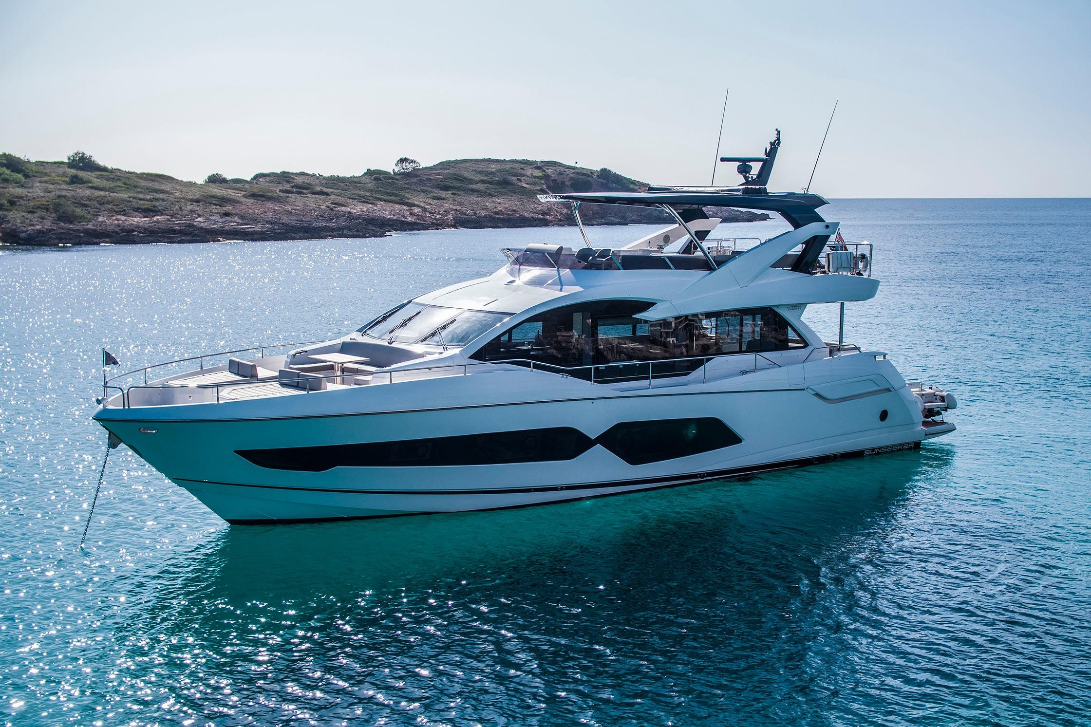 Sunseeker 76 Yacht 2025 Sunseeker 76 Yacht on serene blue waters near a rocky coastline.