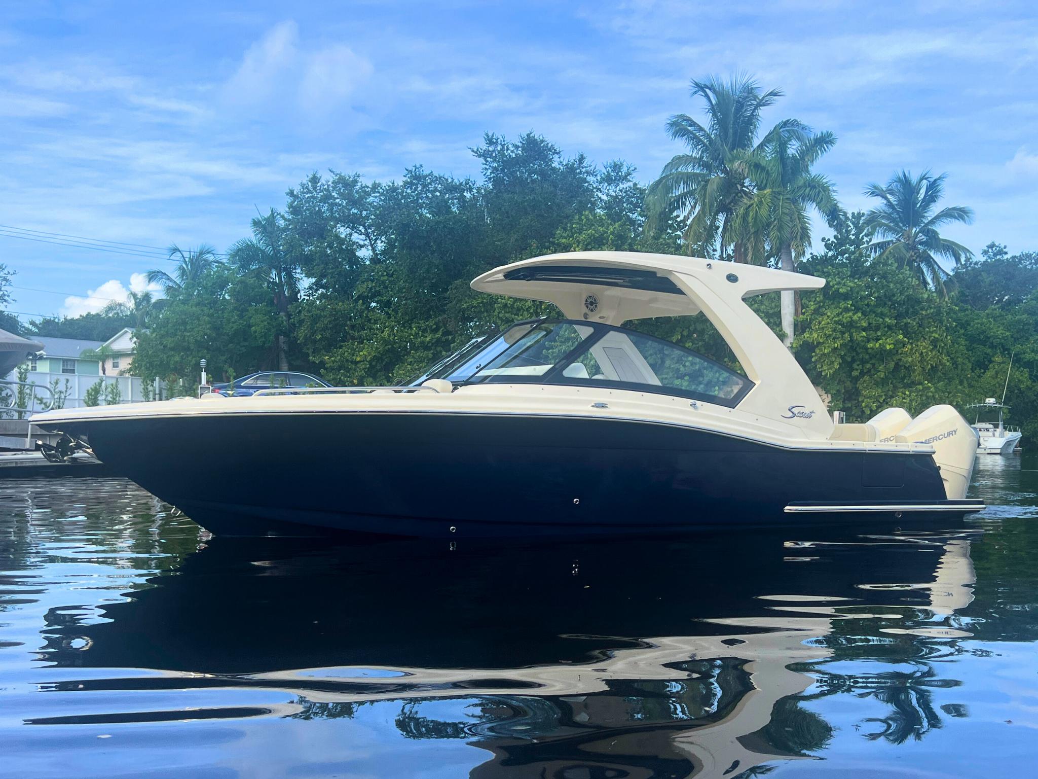 Scout 277 Dorado 2025 Scout 277 Dorado boat on calm water with lush greenery background.