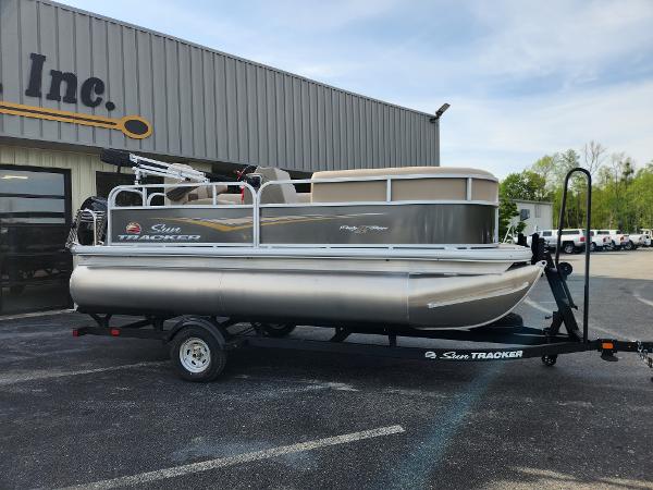 Sun Tracker Party Barge 16 DLX 2025 Sun Tracker Party Barge 16 DLX pontoon boat on trailer outside dealership.