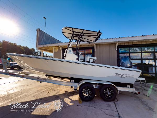 Pathfinder TRS 2200 2024 Pathfinder TRS 2200 boat on trailer outside marine shop, sunny day.