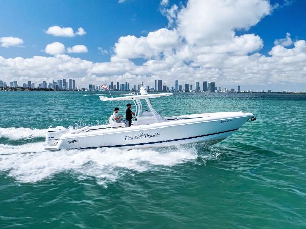 Intrepid 327 Center Console 2017 Intrepid 327 Center Console boat cruising on turquoise water with city skyline backdrop.