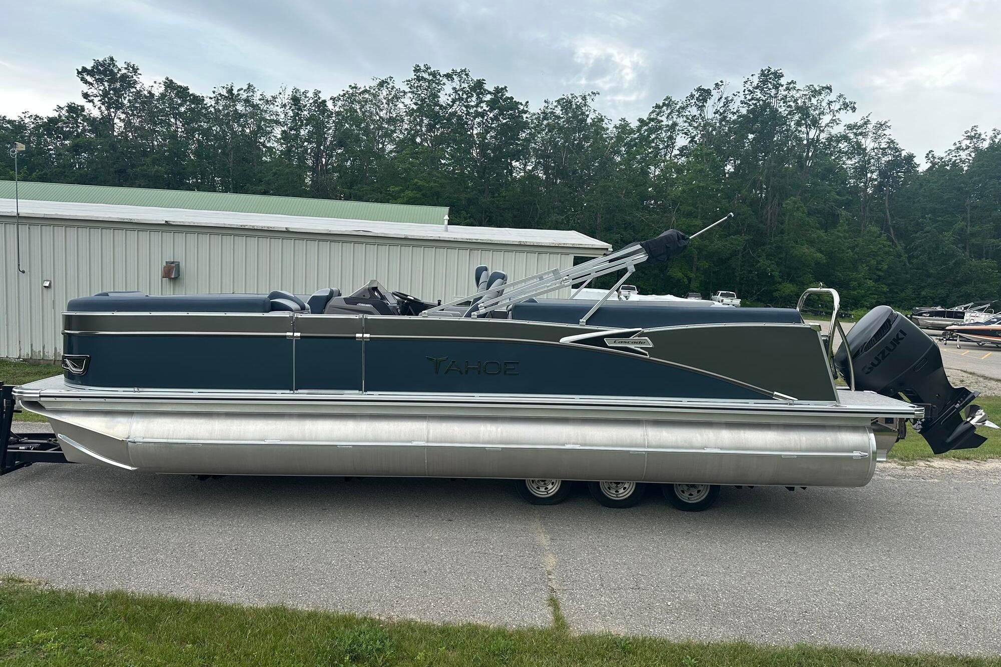 Tahoe 2585 2025 Tahoe 2585 pontoon boat parked outdoors, featuring sleek design and Suzuki outboard motor.