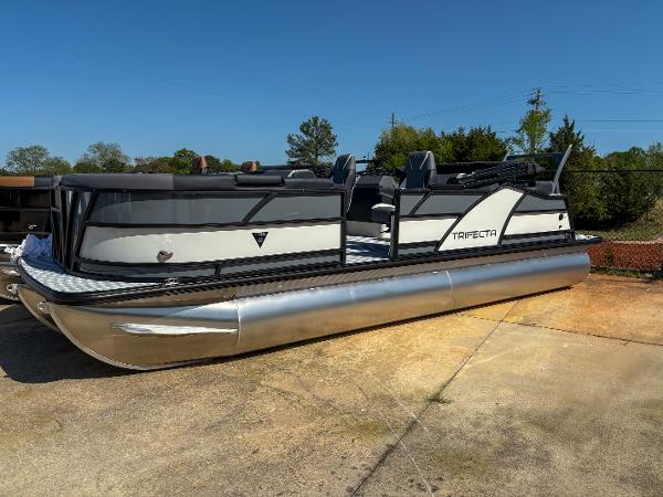 Trifecta 23 RF SS 2025 Trifecta 23 RF SS pontoon boat on concrete, sunny day, side view.