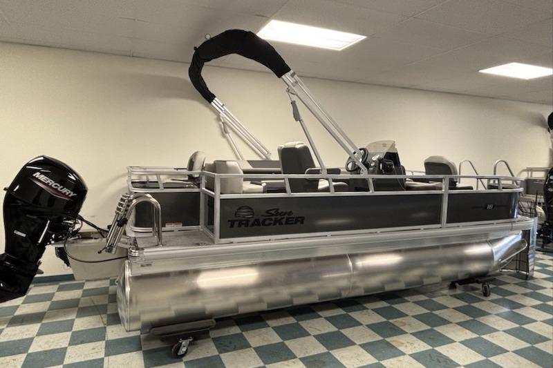 Sun Tracker Bass Buggy 18 DLX 2026 Sun Tracker Bass Buggy 18 DLX pontoon boat with Mercury outboard motor in showroom.