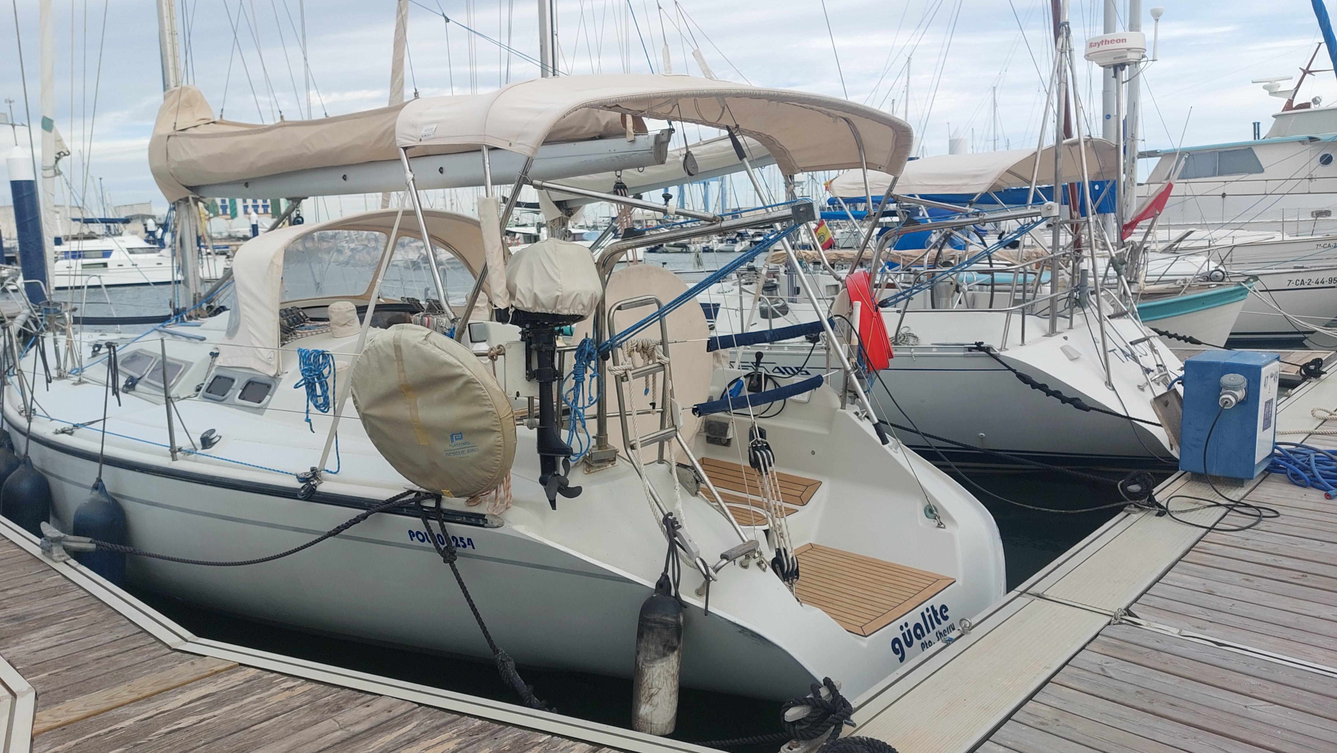 Dehler 38 1987 Dehler 38 sailboat docked at a marina, featuring a beige canopy and wooden deck.