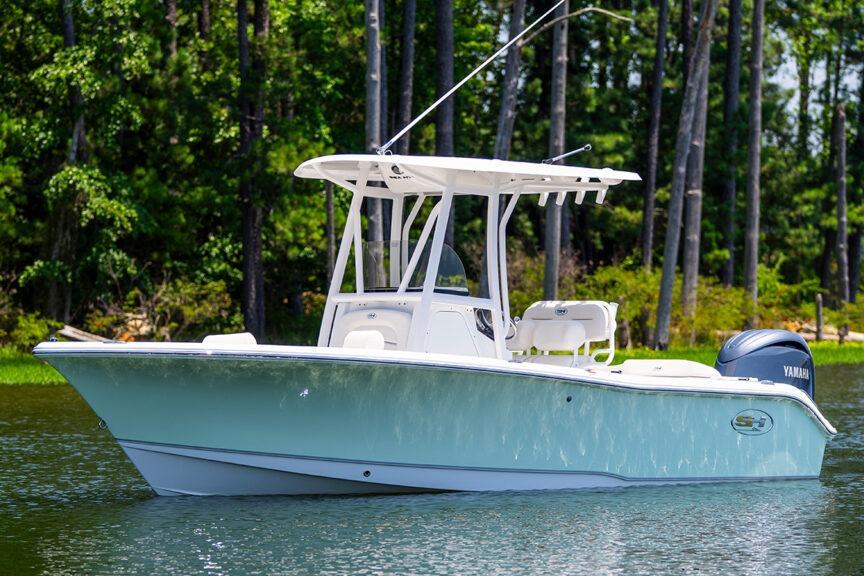 Sea Hunt Ultra 219 2026 Sea Hunt Ultra 219 boat on a serene lake with forest backdrop.