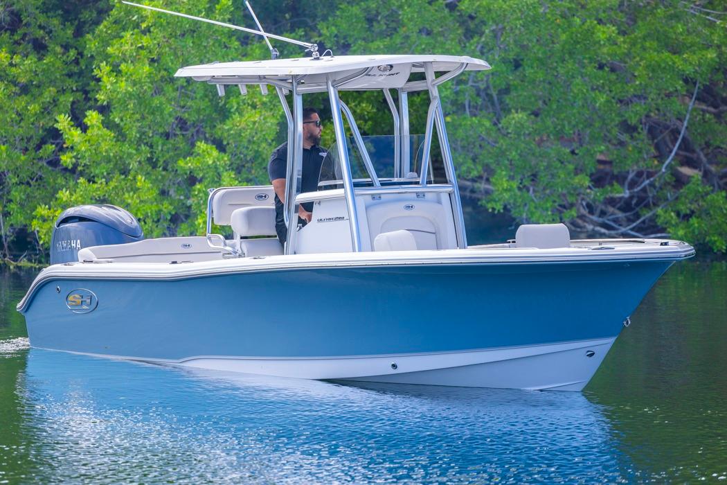Sea Hunt Ultra 219 2026 Sea Hunt Ultra 219 boat cruising on a calm lake with lush greenery.