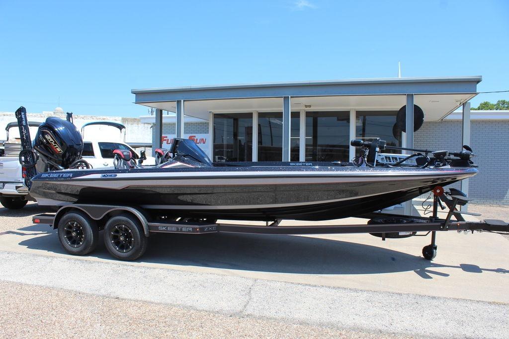 Skeeter ZXE21 2026 Skeeter ZXE21 boat on trailer, parked outside a building under clear blue sky.