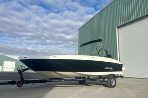 Bayliner Element XL 2016 Bayliner Element XL boat on trailer, parked near large green building under cloudy sky.